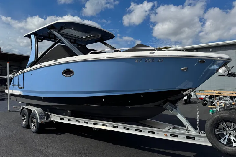 The Image of 2024 Chaparral 280 OSX boat on trailer, blue hull, parked outdoors under cloudy sky. - 0