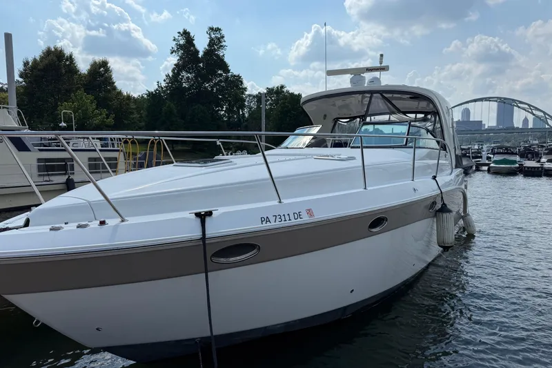 Slide: The Image of 2010 Rinker 400 Express Cruiser docked in a marina, with city skyline in background. - 2