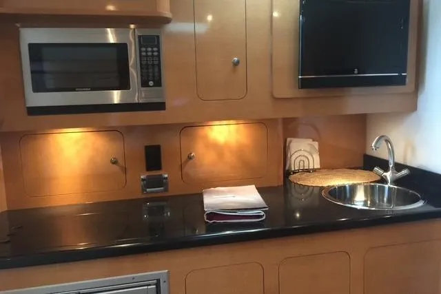 Slide: The Image of 2010 Rinker 400 Express Cruiser kitchen with microwave, sink, and sleek cabinetry. - 23