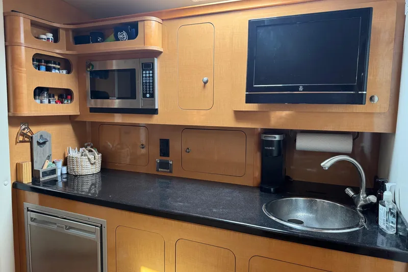 Slide: The Image of 2010 Rinker 400 Express Cruiser kitchen with microwave, sink, and TV. - 28