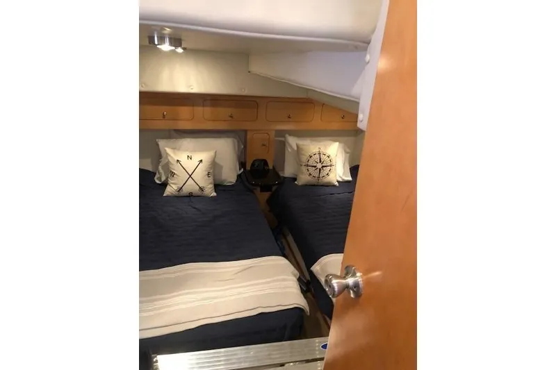 Slide: The Image of 2010 Rinker 400 Express Cruiser cabin with twin beds and nautical-themed pillows. - 40