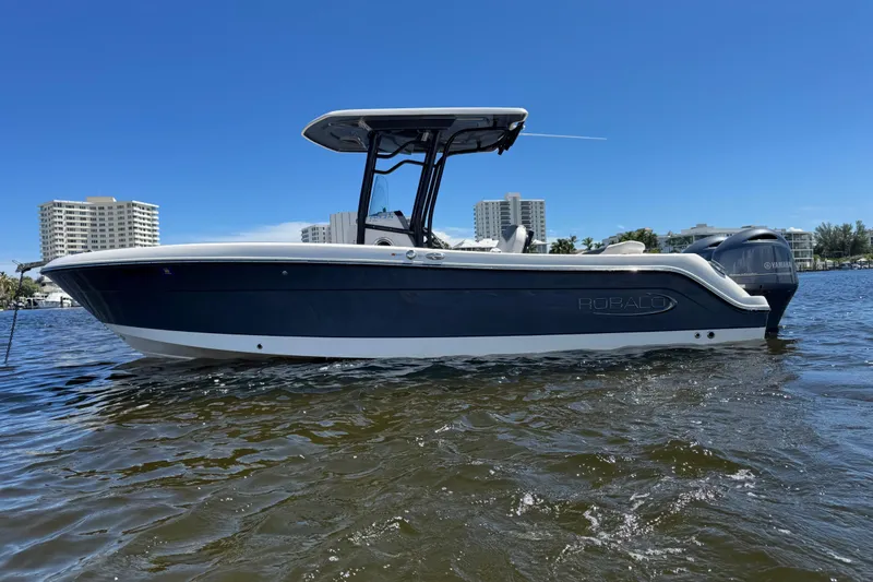 Slide: The Image of 2022 Robalo R242 Center Console boat on water, cityscape background. - 0