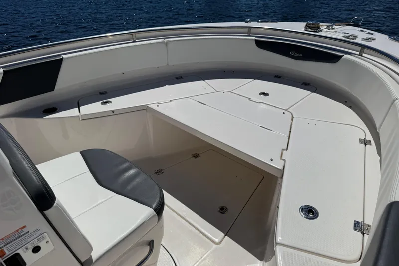 Slide: The Image of 2022 Robalo R242 Center Console boat interior with seating and storage, on calm water. - 9