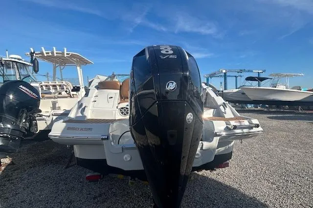 Slide: The Image of 2023 Crownline 250 XSS boat with powerful outboard motor, parked on gravel. - 6