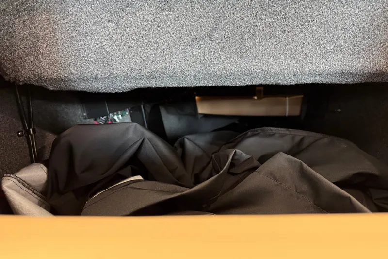 Slide: The Image of Storage compartment in a 2026 Moomba Craz boat, featuring black fabric and carpeted interior. - 31