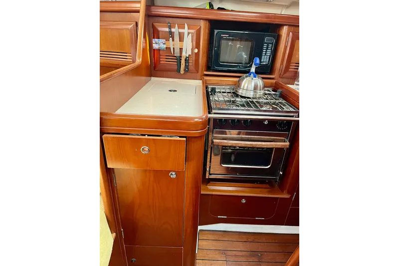 Slide: The Image of 2006 Beneteau Oceanis Clipper 423 yacht kitchen with wooden cabinetry and stainless steel appliances. - 16