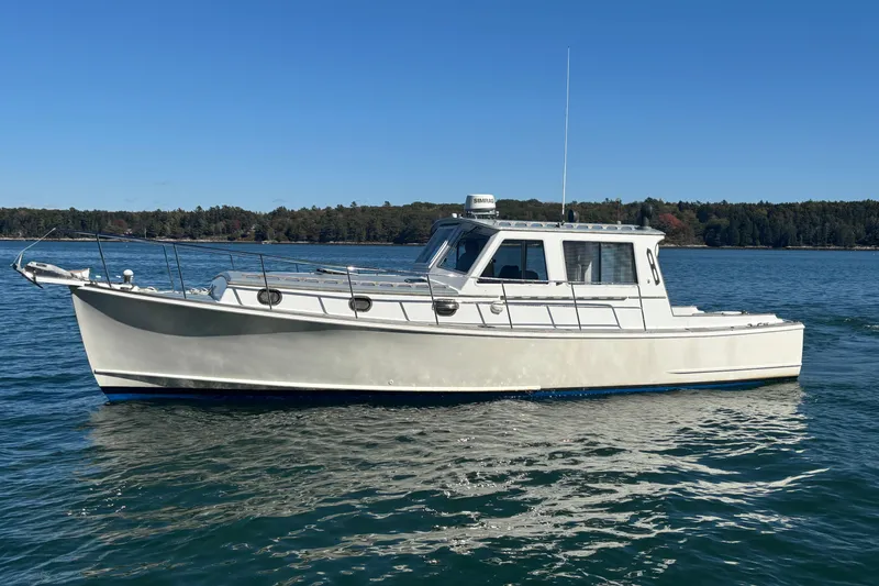 The Image of 1985 Jarvis Newman 36 boat on calm water under clear blue sky. - 0