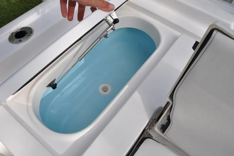 Slide: The Image of 2024 Tidewater 2300 Carolina Bay boat livewell with open lid and blue interior. - 15