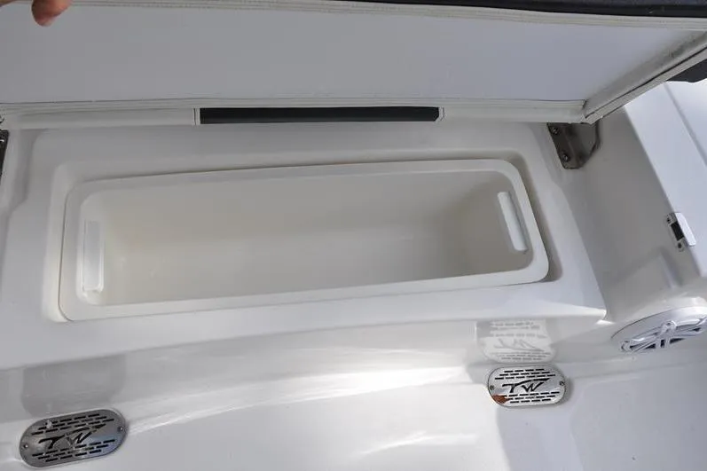 Slide: The Image of 2024 Tidewater 2300 Carolina Bay boat storage compartment, open lid, white interior. - 16