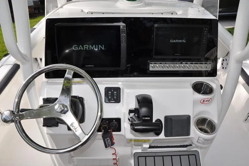 Slide: The Image of 2024 Tidewater 2300 Carolina Bay boat dashboard with Garmin displays and steering wheel. - 24
