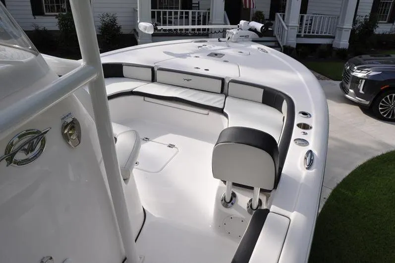 Slide: The Image of 2024 Tidewater 2300 Carolina Bay boat interior with seating and helm, parked near a house. - 27