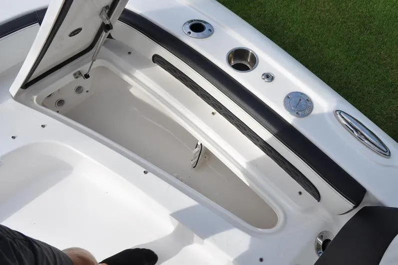 Slide: The Image of 2024 Tidewater 2300 Carolina Bay boat storage compartment with open hatch and cup holders. - 34