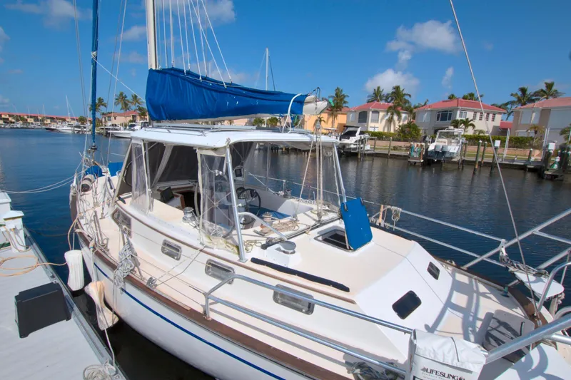 Slide: The Image of 1987 Morgan 43 CC sailboat docked in a sunny marina with palm trees. - 13