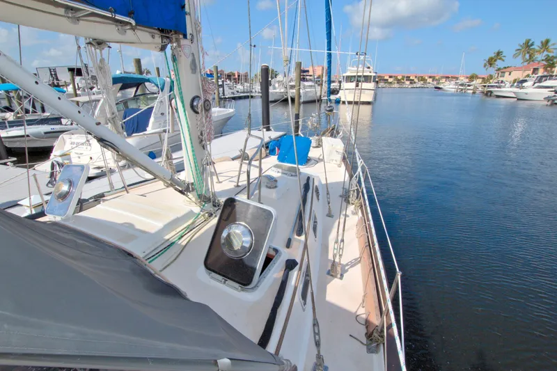 Slide: The Image of 1987 Morgan 43 CC sailboat docked in a sunny marina, surrounded by other boats. - 17