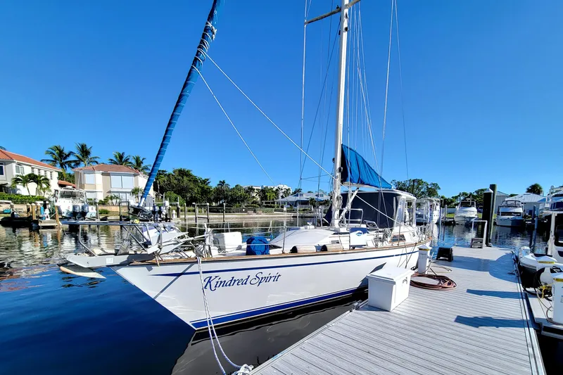 Slide: The Image of 1987 Morgan 43 CC sailboat docked at marina, clear blue sky, waterfront homes. - 2