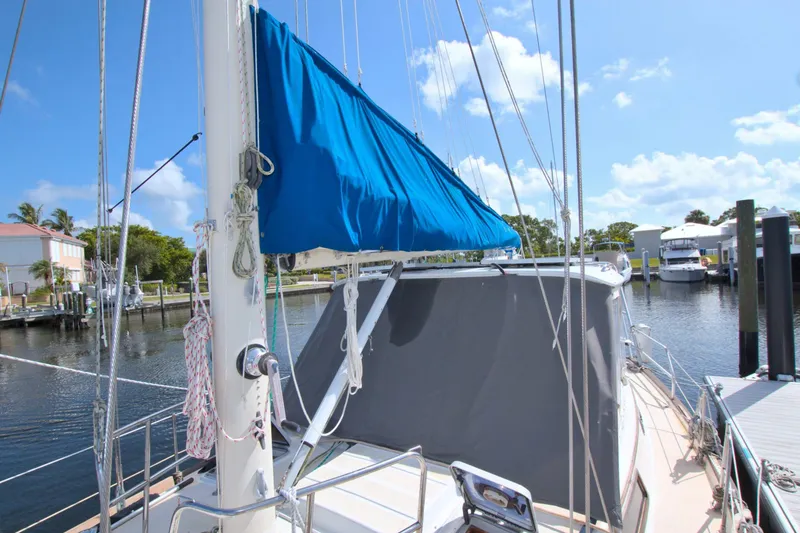 Slide: The Image of 1987 Morgan 43 CC sailboat docked in a sunny marina, featuring blue and gray covers. - 21