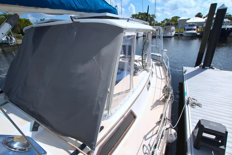 Slide: The Image of 1987 Morgan 43 CC sailboat docked, featuring a covered cockpit and marina backdrop. - 22