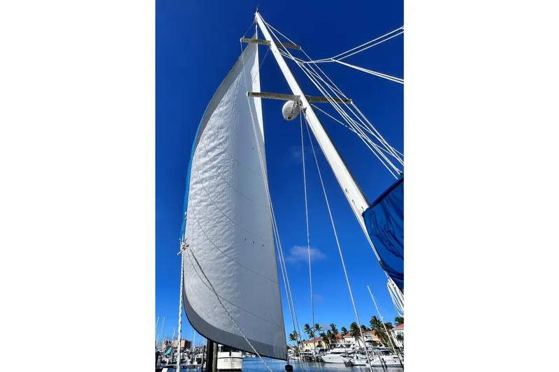 Slide: The Image of 1987 Morgan 43 CC sailboat with full sails against a clear blue sky. - 5