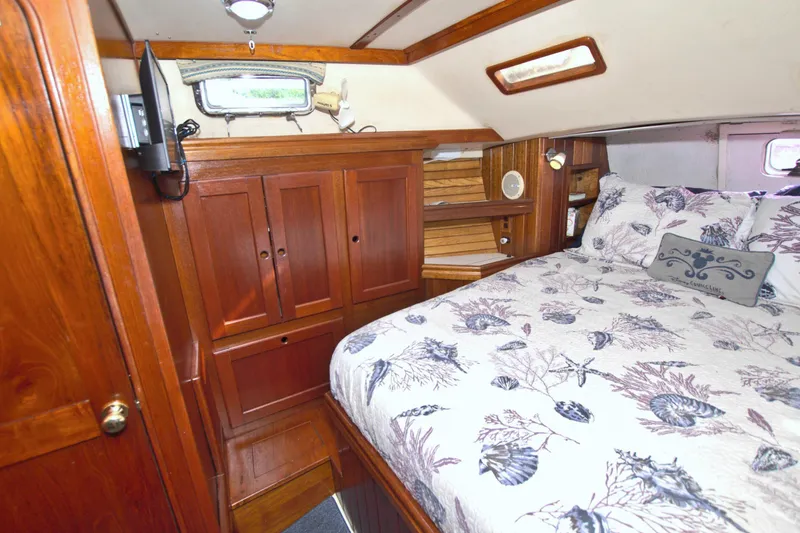 Slide: The Image of Cozy cabin interior of 1987 Morgan 43 CC sailboat with wooden cabinetry and floral bedding. - 55