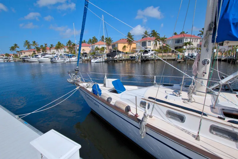 Slide: The Image of 1987 Morgan 43 CC sailboat docked in a sunny marina with palm trees. - 7