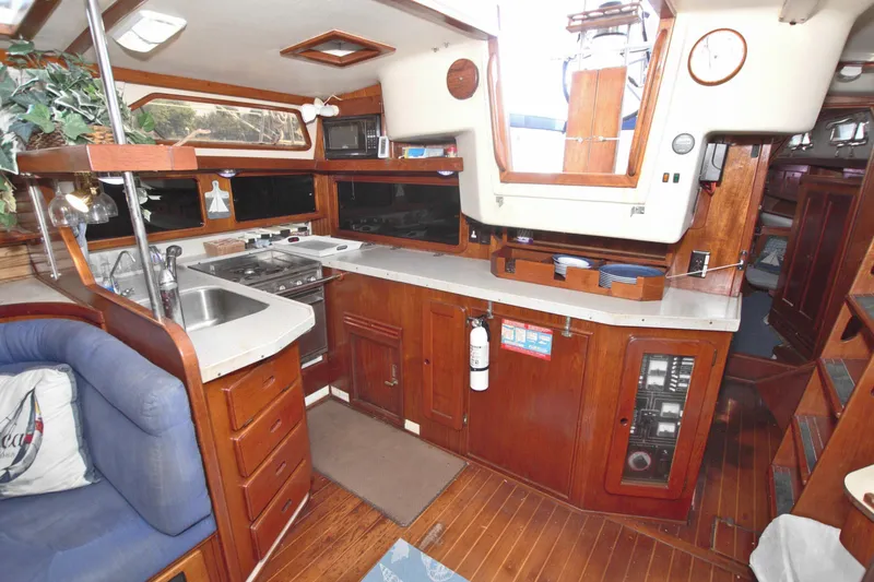 Slide: The Image of 1987 Morgan 43 CC yacht interior with wooden cabinetry, kitchen, and seating area. - 70