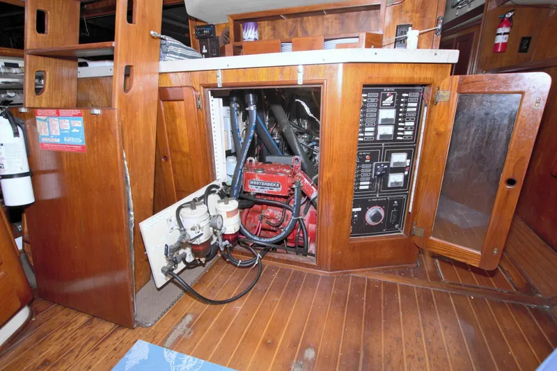 Slide: The Image of Engine room of 1987 Morgan 43 CC sailboat with wooden cabinetry and control panels. - 71
