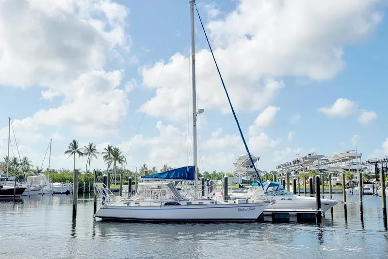 Slide: The Image of 1987 Morgan 43 CC sailboat docked in a sunny marina with palm trees. - 74