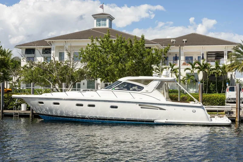 Slide: The Image of 2000 Tiara Yachts 5200 Express docked near a waterfront property, under a clear blue sky. - 2