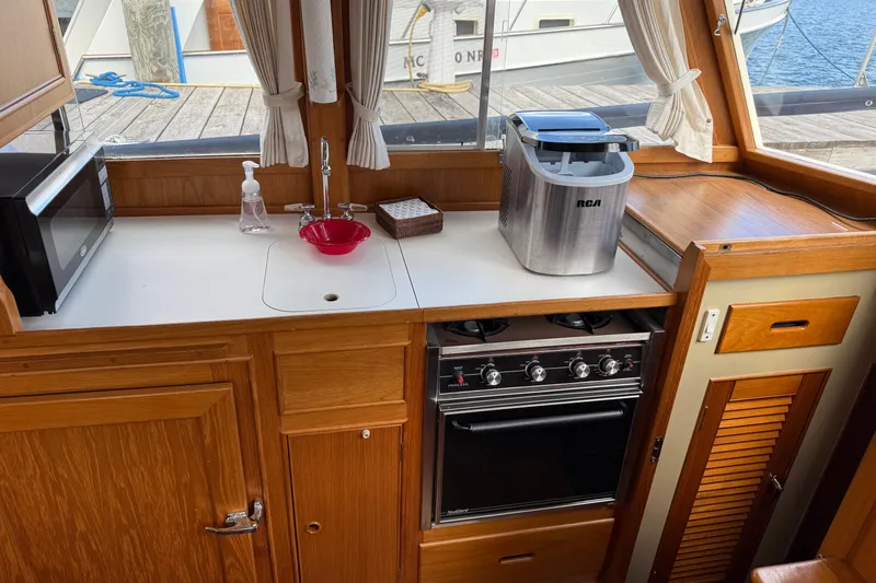 Slide: The Image of 1989 Grand Banks 32 Sedan kitchen with stove, sink, microwave, and ice maker. - 10