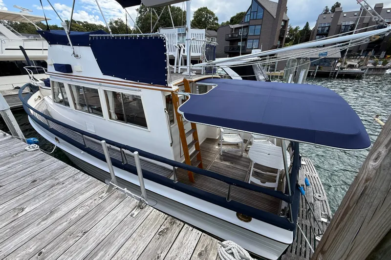 Slide: The Image of 1989 Grand Banks 32 Sedan docked, featuring blue canopy and wooden deck. - 2