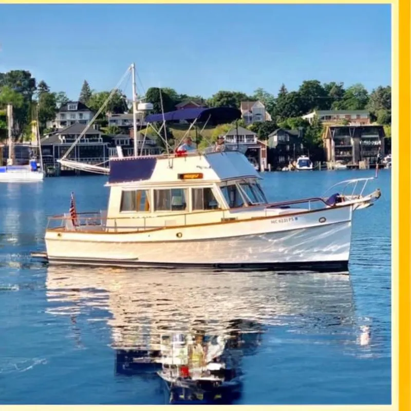 Slide: The Image of 1989 Grand Banks 32 Sedan boat on calm water, with scenic waterfront homes in the background. - 3