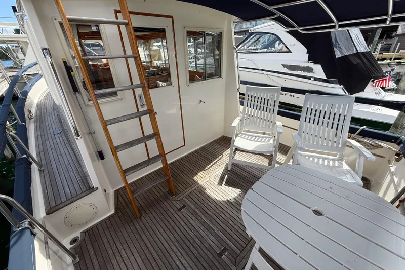Slide: The Image of 1989 Grand Banks 32 Sedan yacht deck with chairs and table, featuring wooden ladder. - 4