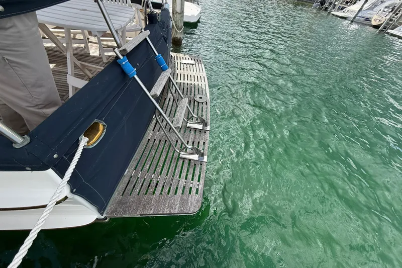 Slide: The Image of 1989 Grand Banks 32 Sedan boat with wooden swim platform on clear green water. - 5