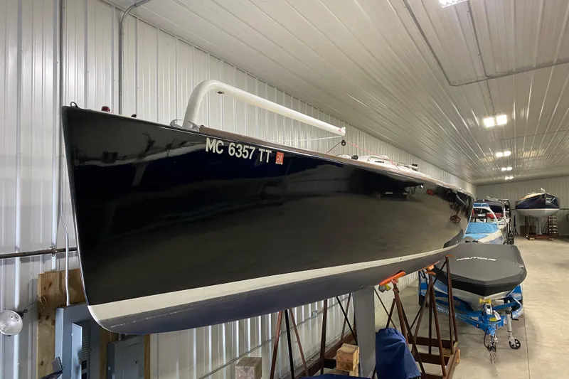 Slide: The Image of 2014 J Boats J/100 sailboat stored indoors, showcasing sleek black hull. - 1