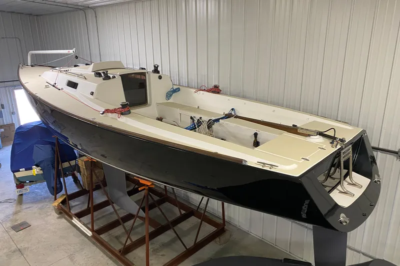 Slide: The Image of 2014 J Boats J/100 sailboat in storage, black hull, white deck, indoor setting. - 8