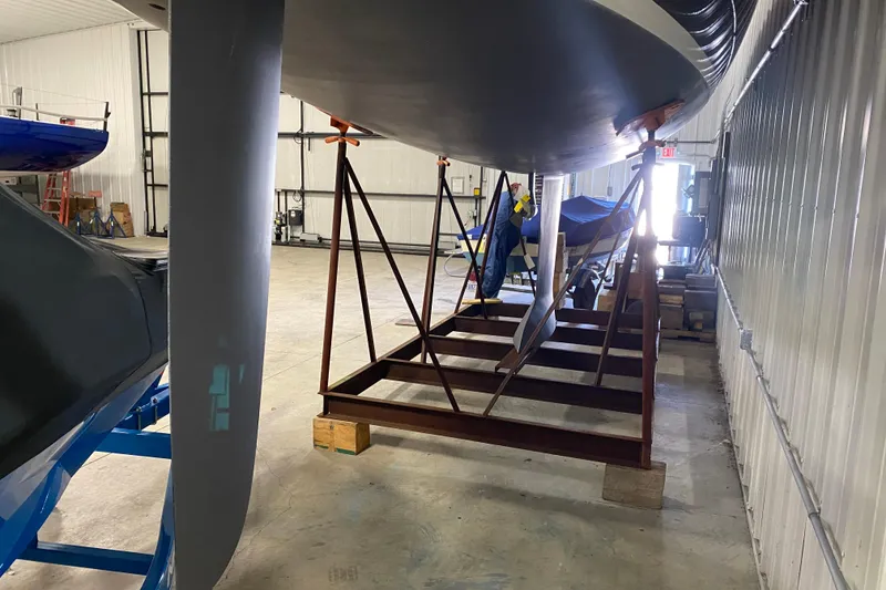 Slide: The Image of 2014 J Boats J/100 sailboat in storage, showing keel and hull in a warehouse. - 9