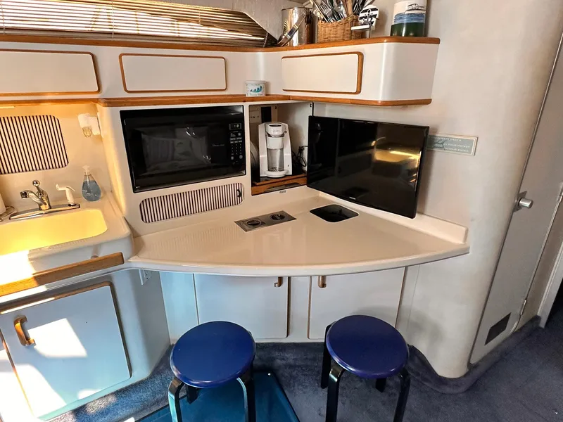 Slide: The Image of 1992 Sea Ray 400 Express Cruiser interior with kitchenette, microwave, and seating area. - 11