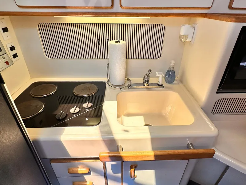 Slide: The Image of 1992 Sea Ray 400 Express Cruiser kitchen with stove, sink, and storage. - 13