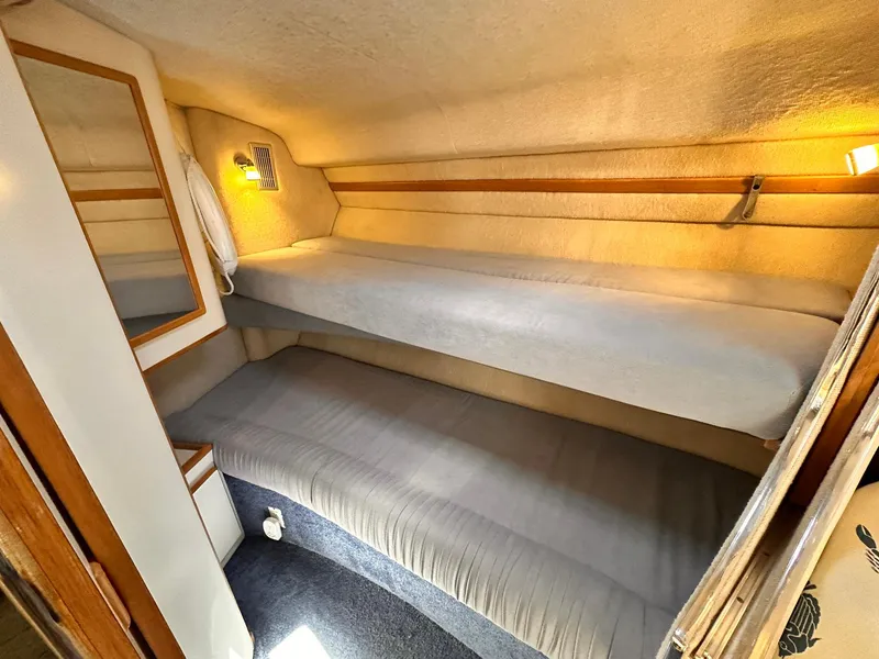 Slide: The Image of 1992 Sea Ray 400 Express Cruiser cabin with bunk beds and cozy lighting. - 17