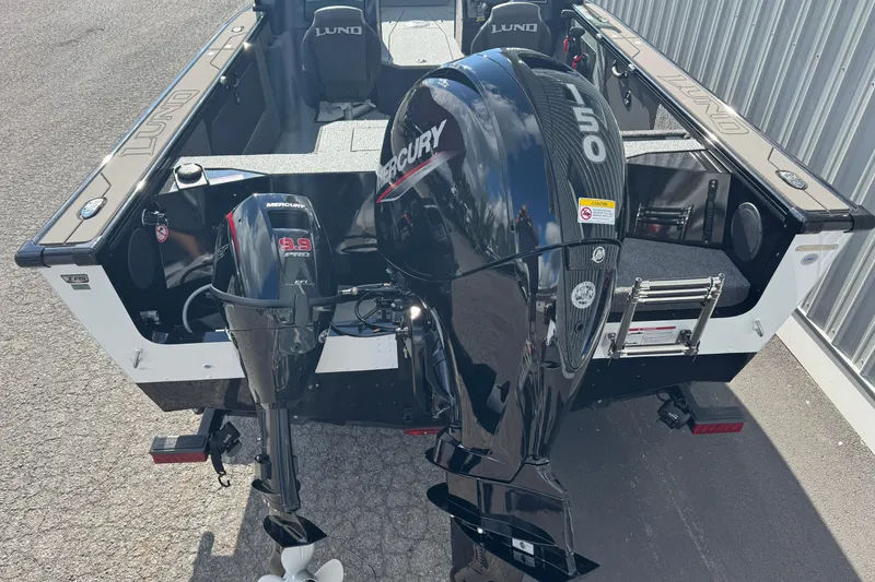 Slide: The Image of 2026 Lund 1875 Fisherman boat with dual Mercury outboard motors, parked on pavement. - 3