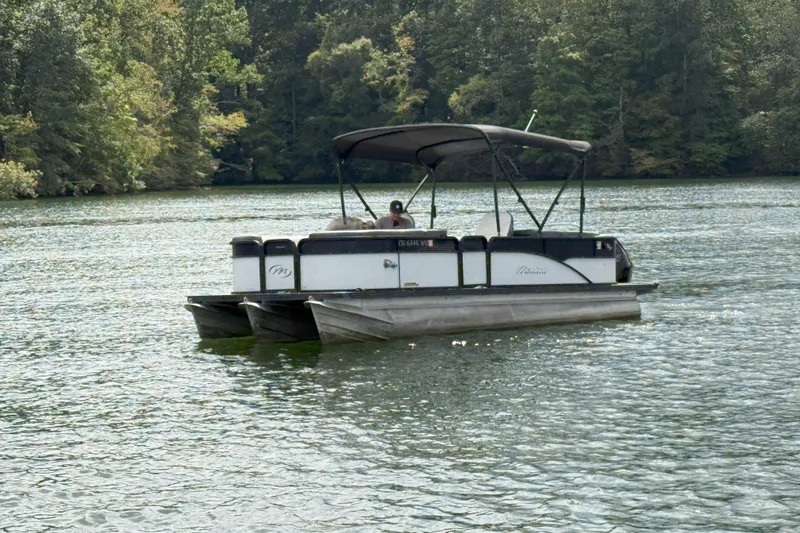 Slide: The Image of 2021 Manitou 22 Aurora LE Standard pontoon boat on a serene lake. - 2