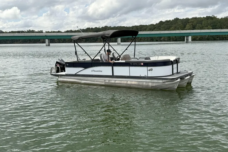 Slide: The Image of 2021 Manitou 22 Aurora LE Standard pontoon boat on a lake with bridge in background. - 5