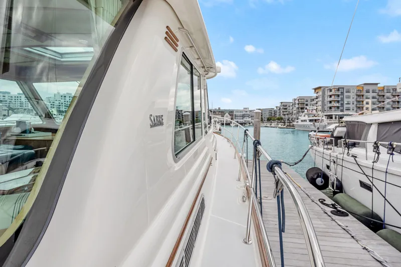 Slide: The Image of 2018 Sabre 48 Salon Express yacht docked at a marina with modern buildings. - 10