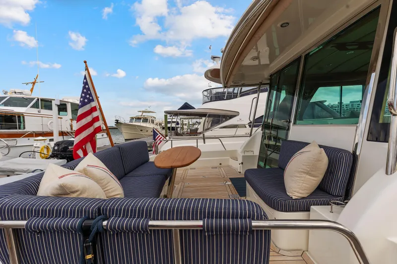 Slide: The Image of 2018 Sabre 48 Salon Express yacht with striped seating and American flag at marina. - 6