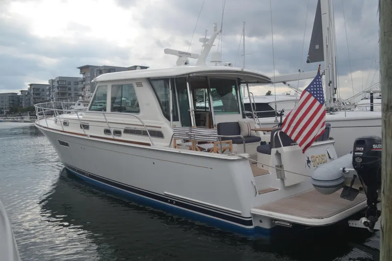 Slide: The Image of 2018 Sabre 48 Salon Express yacht docked, featuring American flag and modern marina backdrop. - 66