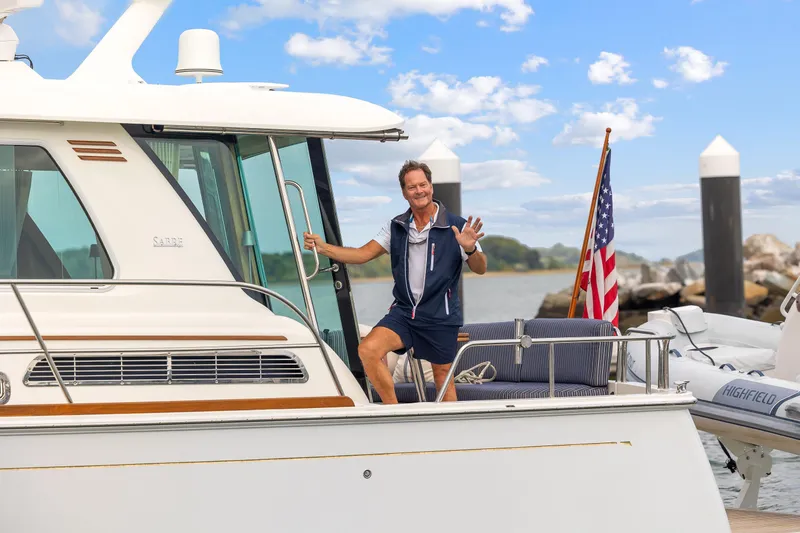 Slide: The Image of Man waving on 2018 Sabre 48 Salon Express yacht, docked with American flag. - 67