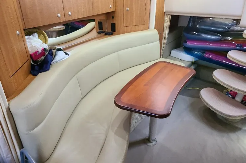Slide: The Image of Interior of 2006 Sea Ray 320 Sundancer with curved seating and wooden table. - 5