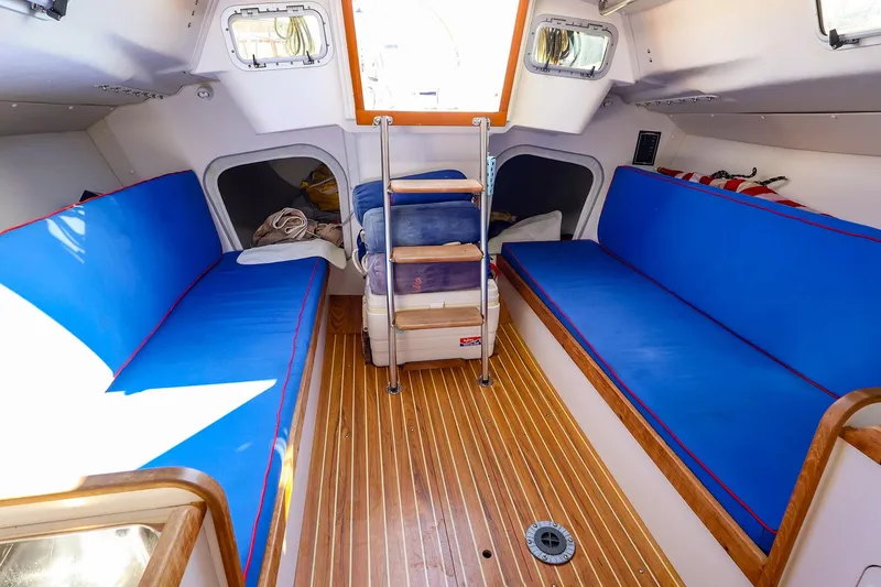 Slide: The Image of Interior of 2000 J Boats J/105 sailboat with blue seating and wooden flooring. - 19