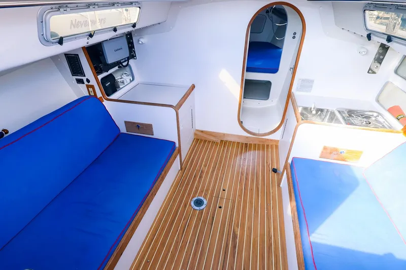 Slide: The Image of Interior of 2000 J Boats J/105 sailboat with blue seating and wooden flooring. - 21