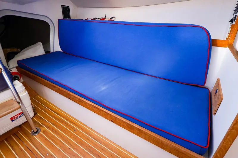 Slide: The Image of Interior of 2000 J Boats J/105 with blue cushioned seating and wooden flooring. - 22